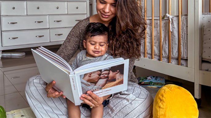 Mother and baby reading baby memory book and smiling lovingly